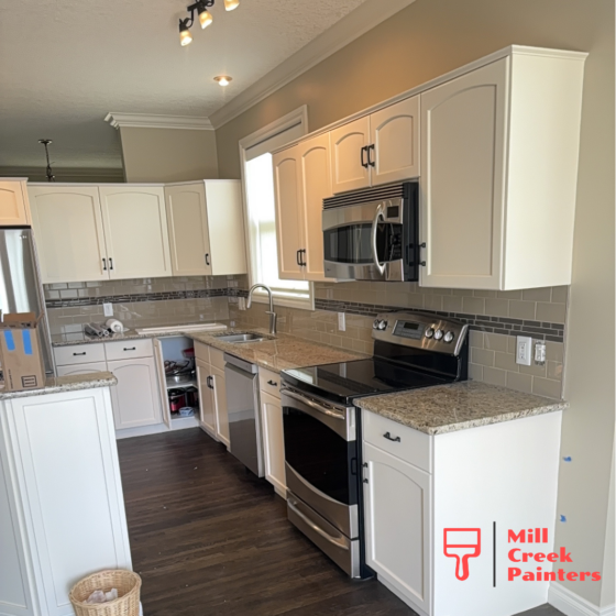Professionally painted white kitchen cabinets in Cochrane, Alberta with quartz countertops and subway tile backsplash.